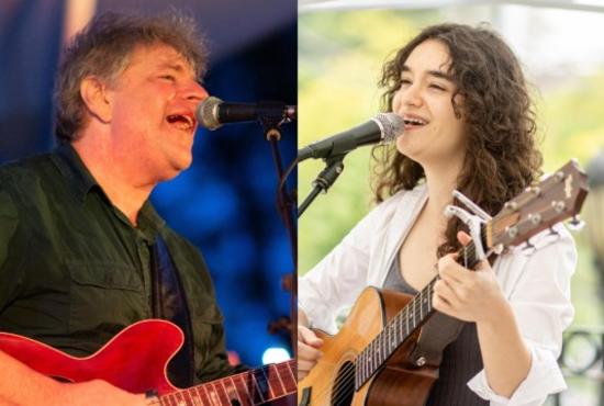 Two performers hold guitars and sing into microphones.
