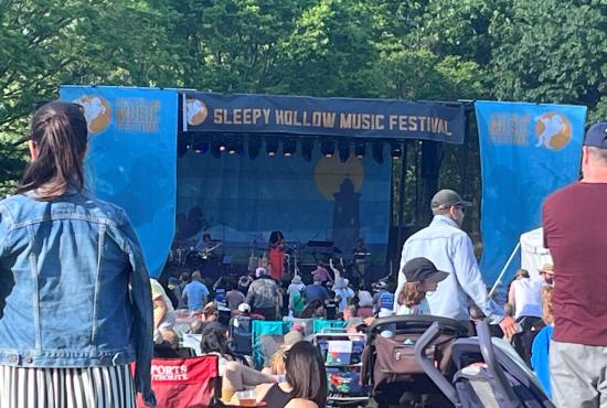 A crowd is gathered on a sunny day in front of the stage at the Sleepy Hollow Music Festival.