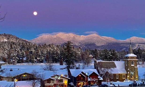 Aerial view of shops and a church in Lake Placid covered in snow with the Adirondack Mountains in the distance