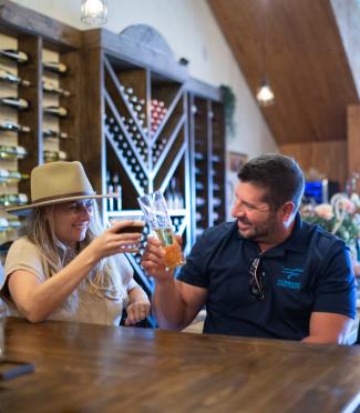 Man and woman in a hat tasting at a bar
