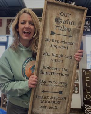 Amber, co-owner, poses for a photo with a sign she made describing their studio rules