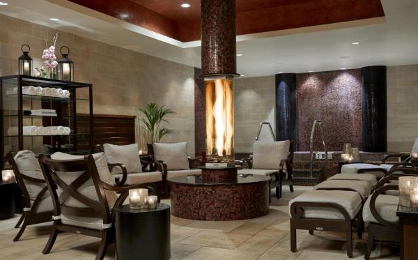 A spa quiet room with a fireplace in the center surrounded by lounge chairs