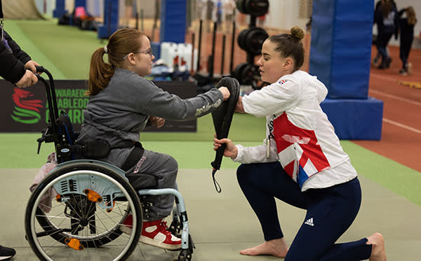 A girl in a wheelchair and a coach boxing sparring.