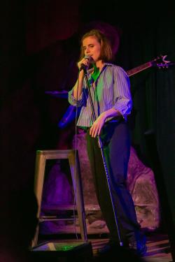 Comedian Elizabeth Spears on stage speaking into a microphone