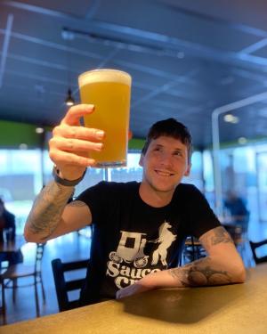 man smiling and holding up his beer