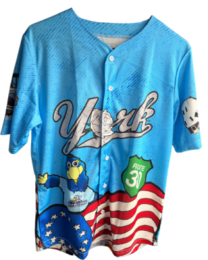 the exclusive, limited edition jersey that the York Revolution created in partnership with Explore York. It features key landmarks like the Haines Shoe House, multiple trains, the Electric Man at the York County History Center, pretzels, and more. All of this with a large white rose front and center on the blue jersey, right next to Downtown (York Revolution's mascot)