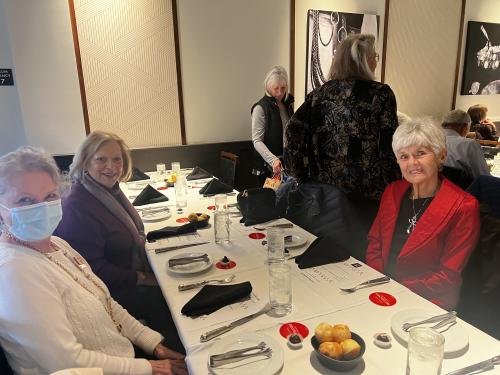 Three older women smile at a dining table at the Visit Albuquerque Holiday Volunteer Luncheon