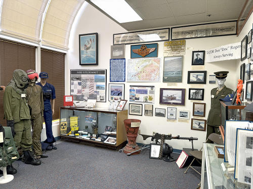 Military exhibit with photos, maps, and vintage uniforms at the Alaska Veterans Museum.