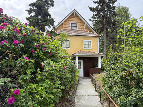 View of path leading up to the bright yellow Oscar Anderson House Museum in Bootleggers Cove, Anchorage, Alaska.