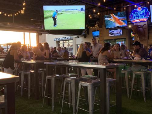 Big screen TV and patrons sitting at high table tops at Little Woodrow's Sports Bar