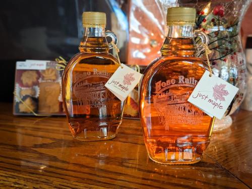 Two glass jars filled with maple syrup with "Hobo Railroad" and an image of a train crossing a bridge edged on the front