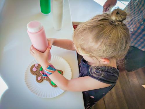 A young girl uses a squeeze bottle to put pink icing on a gingerbread cookie at Santa's Village