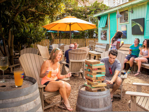 colorful courtyard of Lighthouse Beer and Wine at Wrightsville Beach with people drinking, mingling, and playing jenga