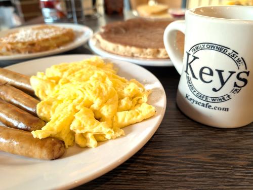 Breakfast items--eggs, sausage, pancakes and French toast--with a coffee featuring Key's Cafe logo on cup.
