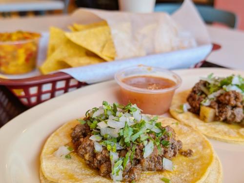 Two soft shell tacos with salsa with an order of chips and mango salsa and horchata drink.