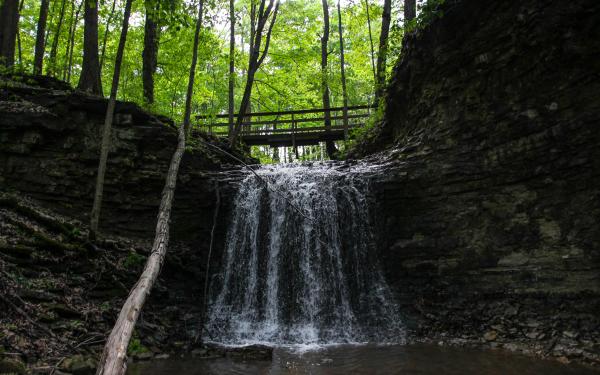 A small bridge crosses over a waterfall at Charlestown State Park.