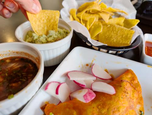 Birria Tacos at Good Bites Mexican Grill with a side of chips and guacamole with chip being dipped