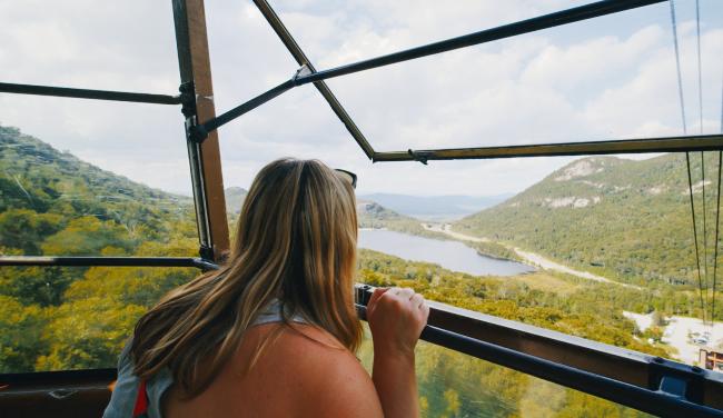 Cannon Mountain Aerial Tramway - Woman Enjoying the View from Tram with Lake and Mountains Below