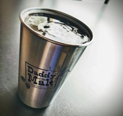 Stainless-steel pint glass full of beer, featuring the Daddy of the Malt logo from Cheyenne, WY.