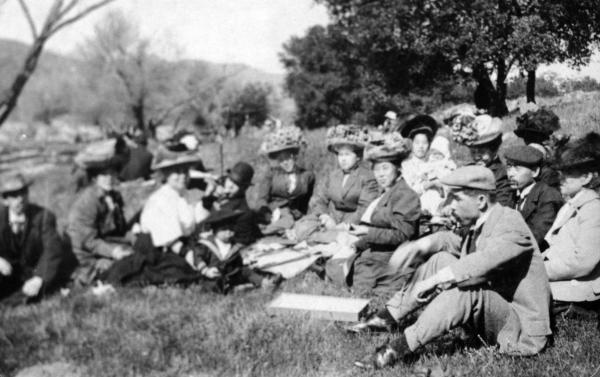 Group of people sit in grass having picnic
