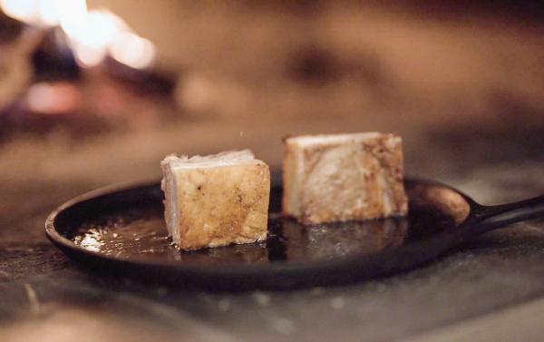 Pork belly on cast iron pan next to fire