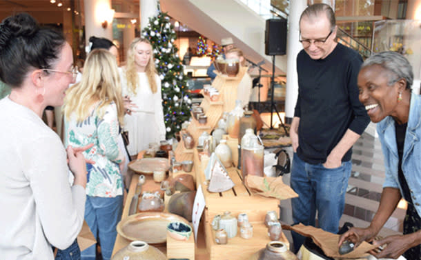 Men and women shop at tables of crafts and holiday decorations