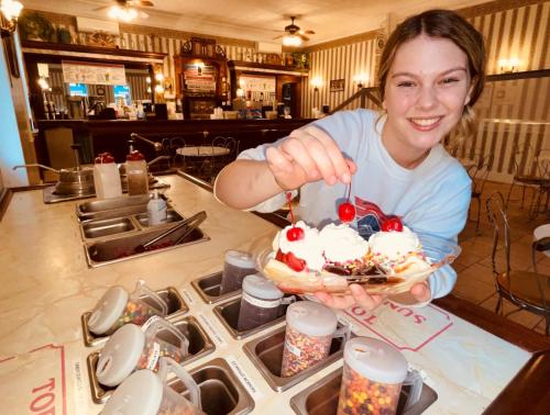 A teenage girl puts the last cherry on top of a banana split at the Peppermint Saloon at Clark's Bears