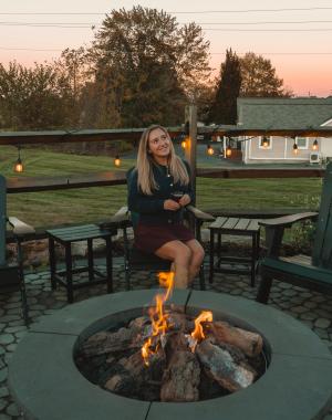 Content Creator Taylor Deer sitting beside the fire on the patio at Jackass Brewery in Lewisburg.