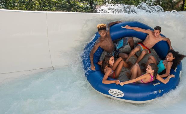 A group of people make their way along the Mammoth River in a giant blue inflated raft at Splish Splash water park