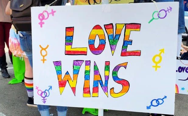 A sign that reads "Love Wins" in a rainbow of colors at Jamestown Pride