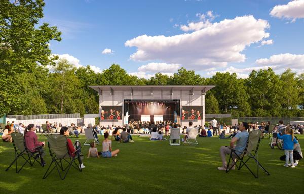 Families and friends sitting on grass in front of an open stage at Freeman Arts Pavilion.
