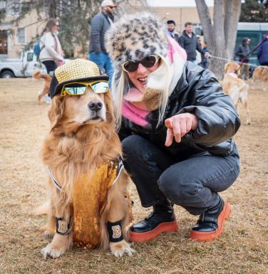 A golden retriever dressed up like a rock star with a costumed owner