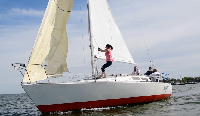 A woman hoists a sail on a sail boat