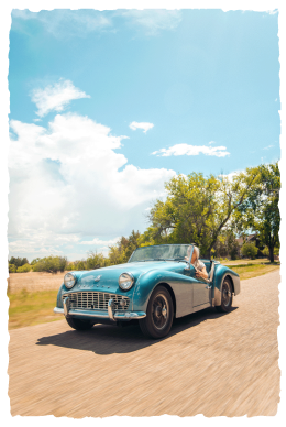 Bria driving her classic car down a dirt road
