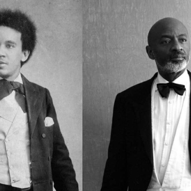 2 men in a black and white picture stood side by side in suits