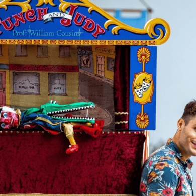 A person leaning against a punch and judy stand with the puppets lying on the stage.