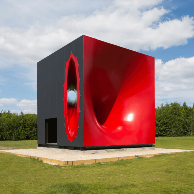 An artwork that looks like a large red box in a field.