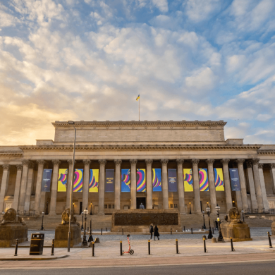 St George's Hall exterior with Eurovision banners, a blue sky and the sun setting to the left