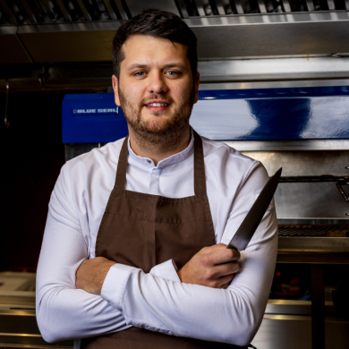 An image of Chef Daniel Heffy in a kitchen holding a knife.