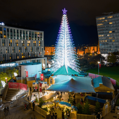 A large christmas tree at Liverpool ONE with stalls around the base of it.