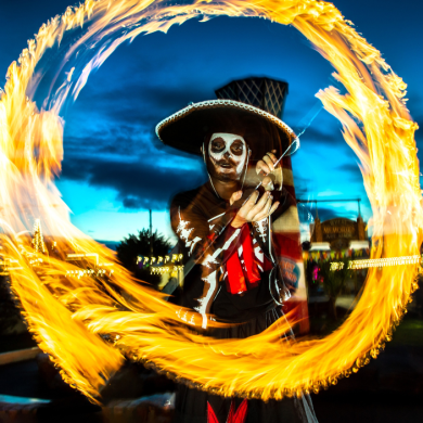 A man dressed as a skeleton playing with fire.
