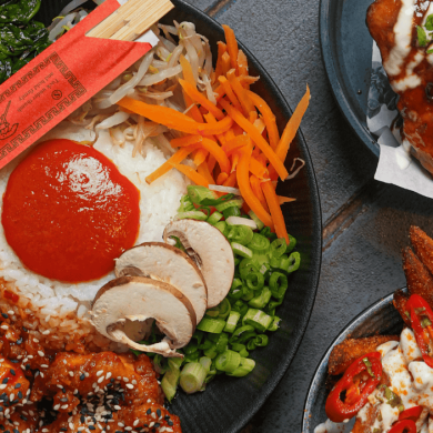 Three plates with different types of food on including rice, chips and chicken.