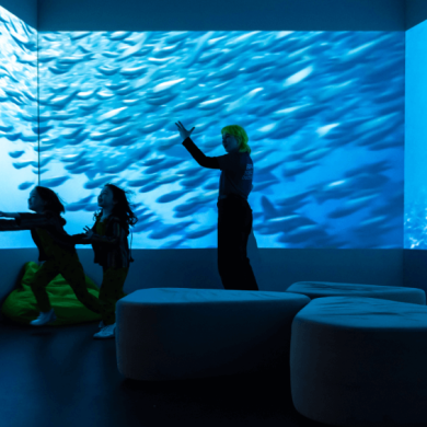 People inside a room full of screens with fishes on