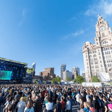 The eurovision village fan zone with a large stage and a crowd of people in front of the royal liver building.