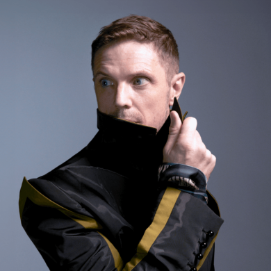Jake Shears wearing a coat looking away from the camera