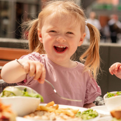 A young girl smiling and eating food