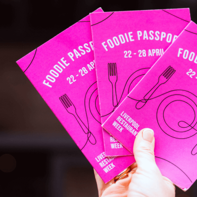A photo of someone holding pink booklets that have Foodie Passports written on them.