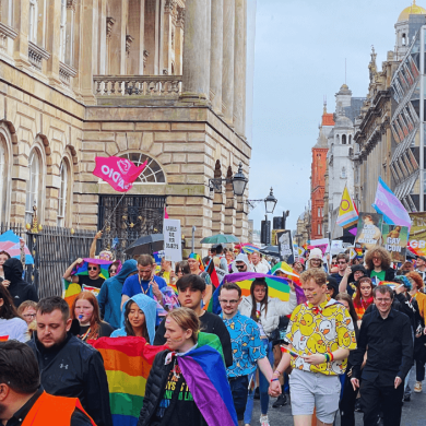 The Pride in Liverpool March passing the Liverpool Town Hall - people are dressed in colour and are carrying pride flags