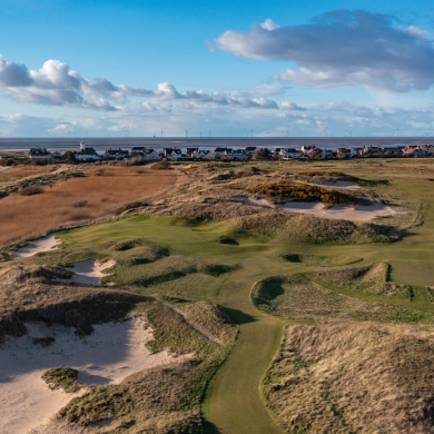 The Royal Liverpool golf course with green grass on the course and grassy bunkers.