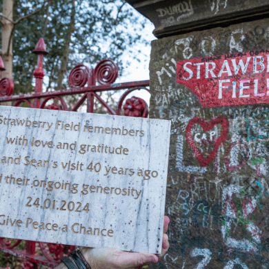 A rectangle stone with writing engraved into it outside the gates at Strawberry Field